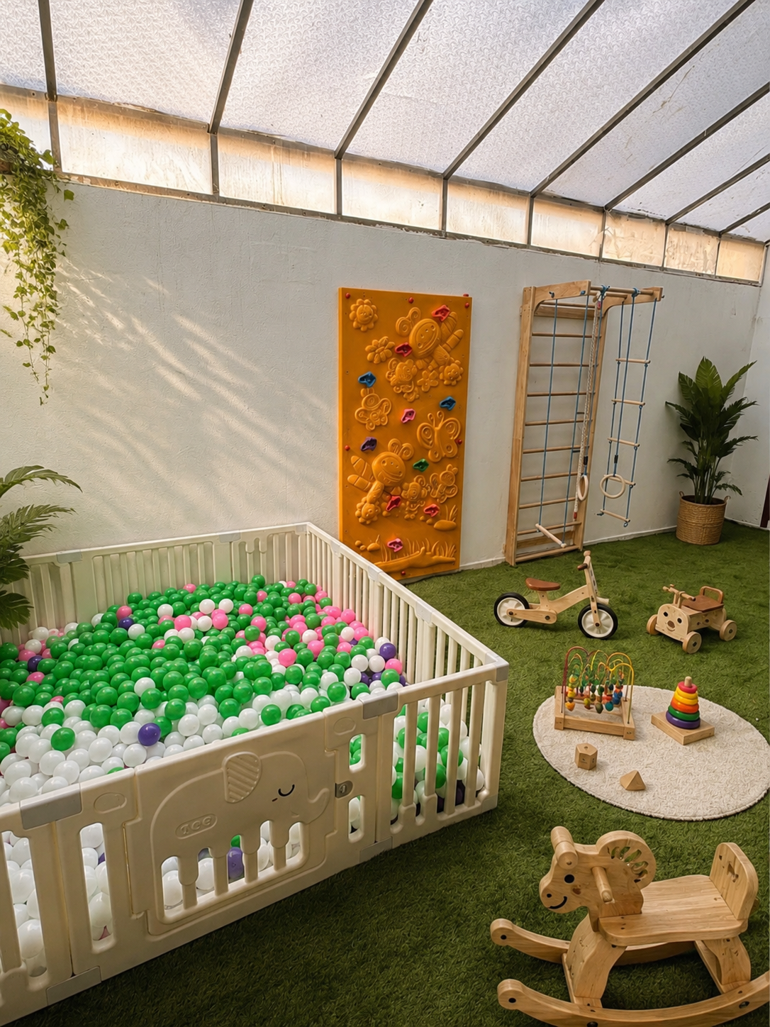 Outdoor play zone with ball pit, climbing wall, and wooden toys at Maker Fingers